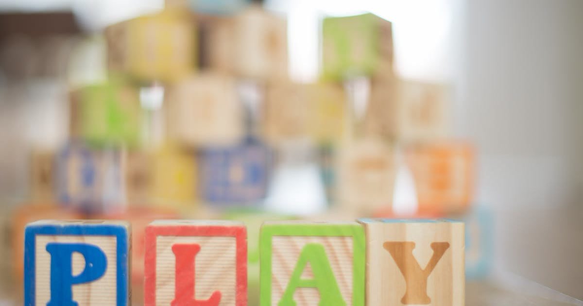 Colorful wooden blocks spelling PLAY on a wooden surface